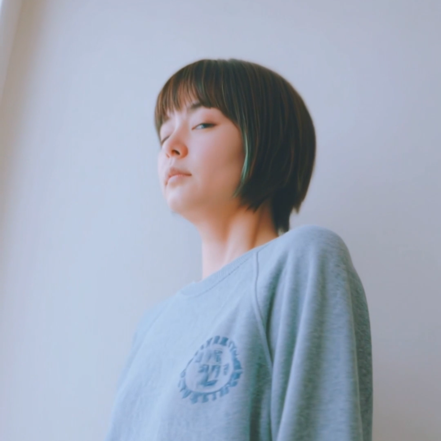 札幌市東区の美容室「ハートシェイプドボックス」のヘアスタイル作例。赤みのブラウン系ヘアカラーが美しい、ベレー帽をかぶり頬杖をつく女性のクローズアップポートレート。個性を引き出すデザインカラー。