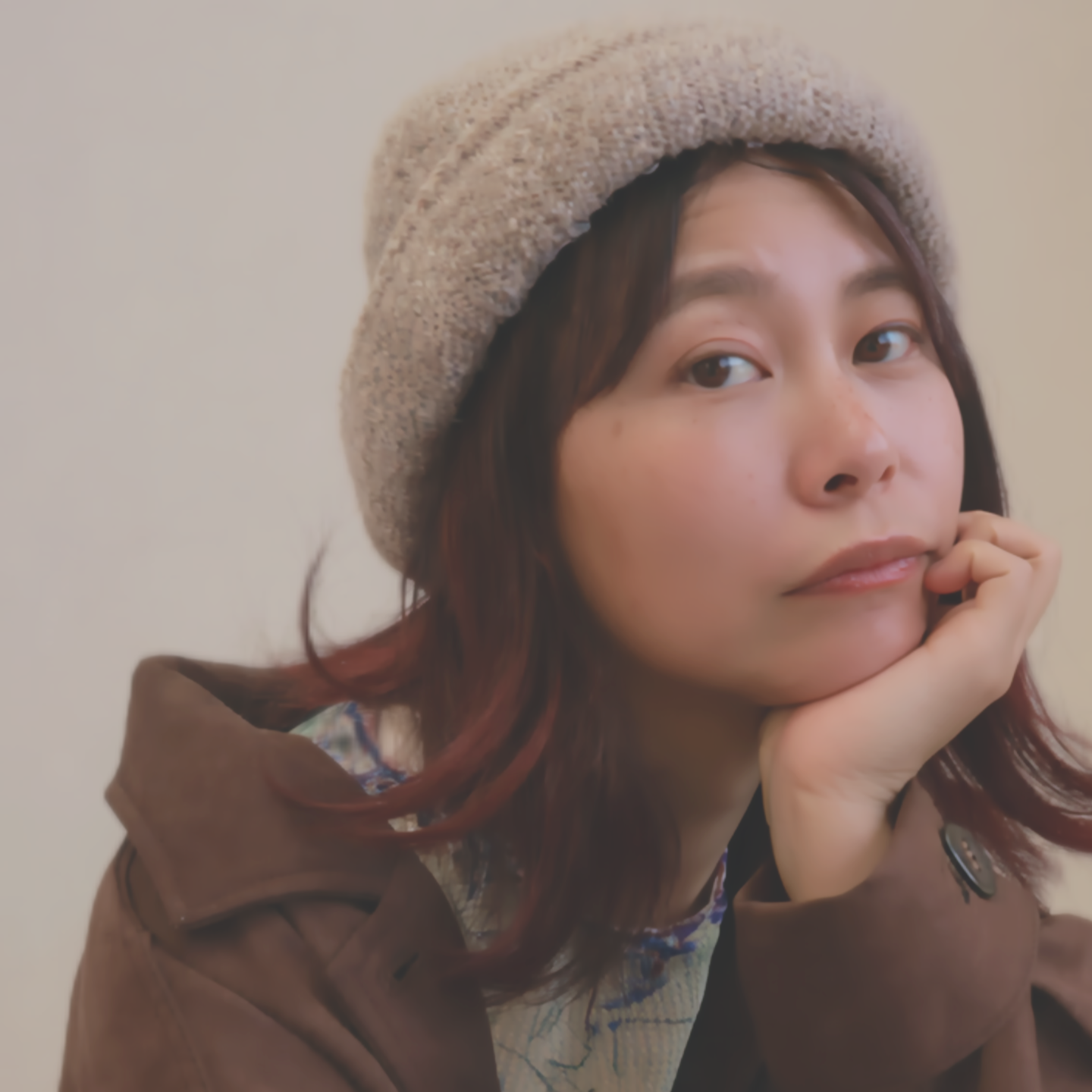 札幌市東区の美容室「ハートシェイプドボックス」のヘアスタイル作例。赤みのブラウン系ヘアカラーが美しい、ベレー帽をかぶり頬杖をつく女性のクローズアップポートレート。個性を引き出すデザインカラー。