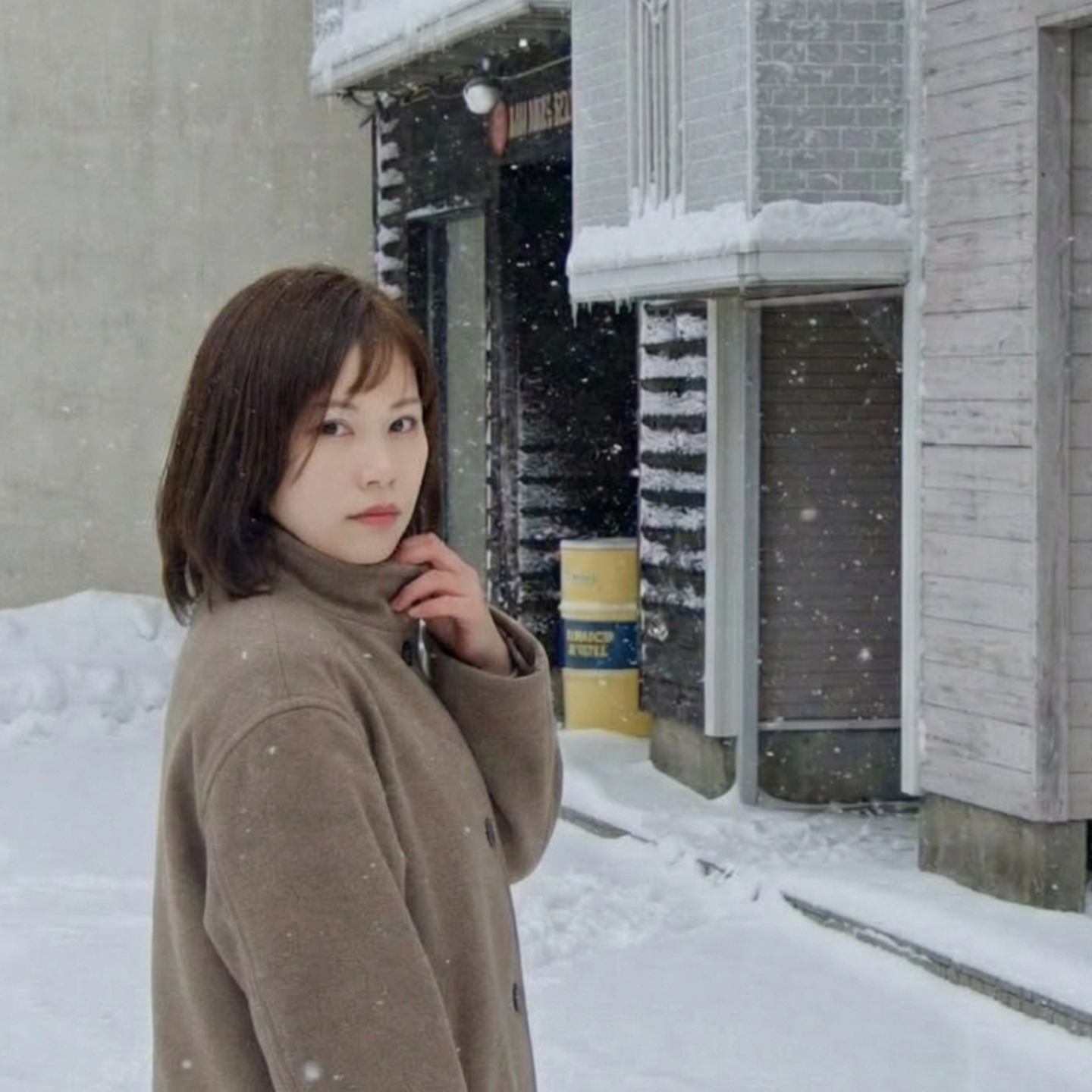 札幌市東区の美容室「ハートシェイプドボックス」のヘアスタイル作例。白い木の壁を背景に、デニムシャツを着て頬杖をつく女性のクローズアップ。鮮やかなオレンジ系のヘアカラーで、生き生きとした表情を演出。