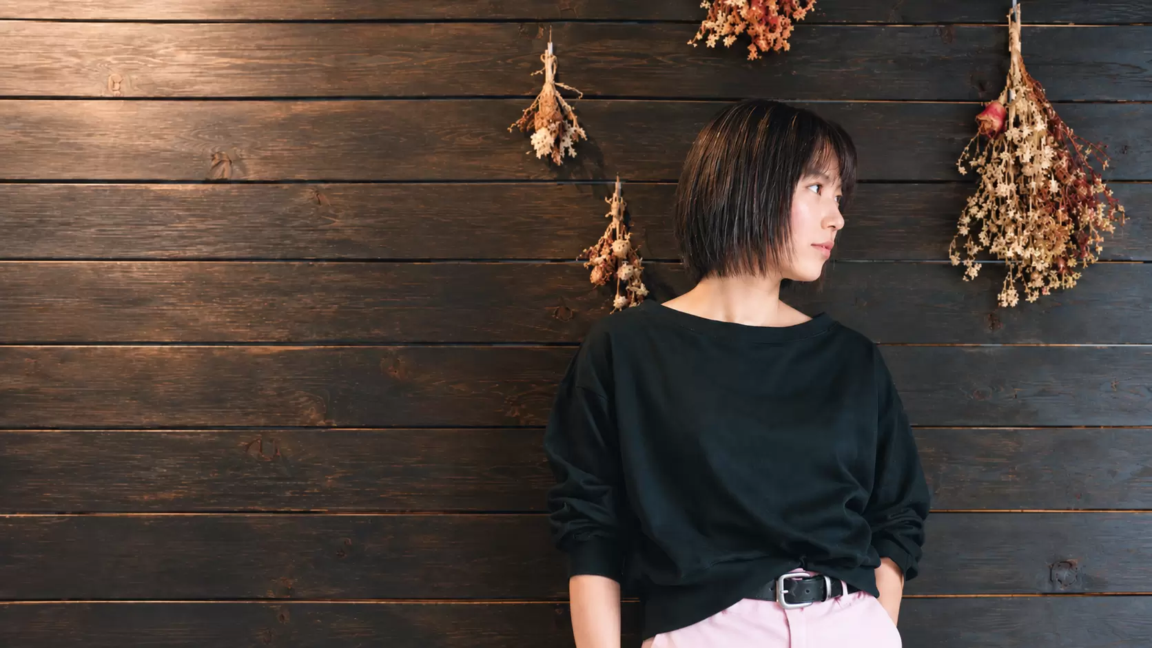 木の壁とドライフラワーを背景にしたボブスタイルのヘアポートレート