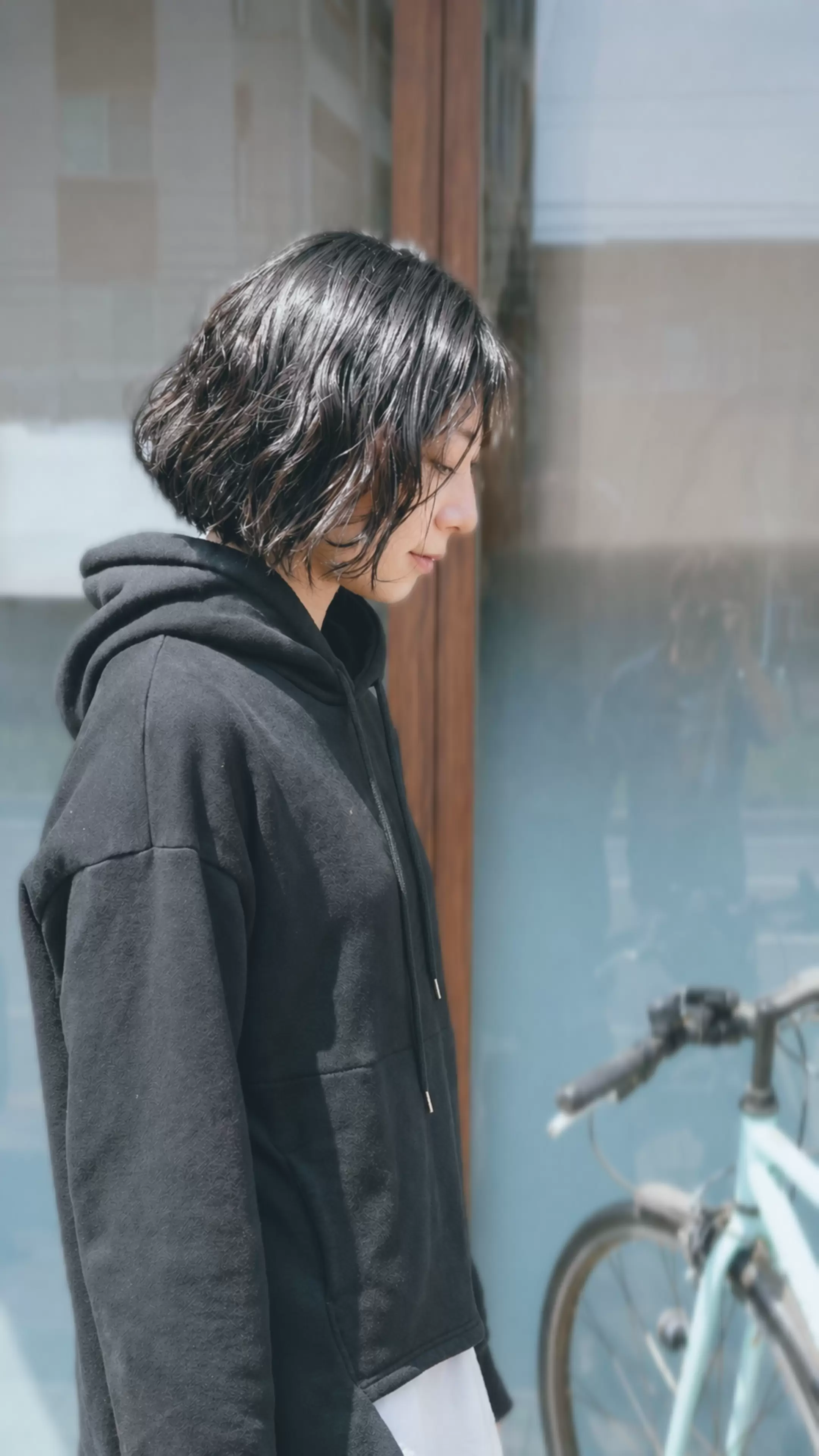 自転車のある街角で撮影した、自然な質感のボブスタイルのヘアポートレート