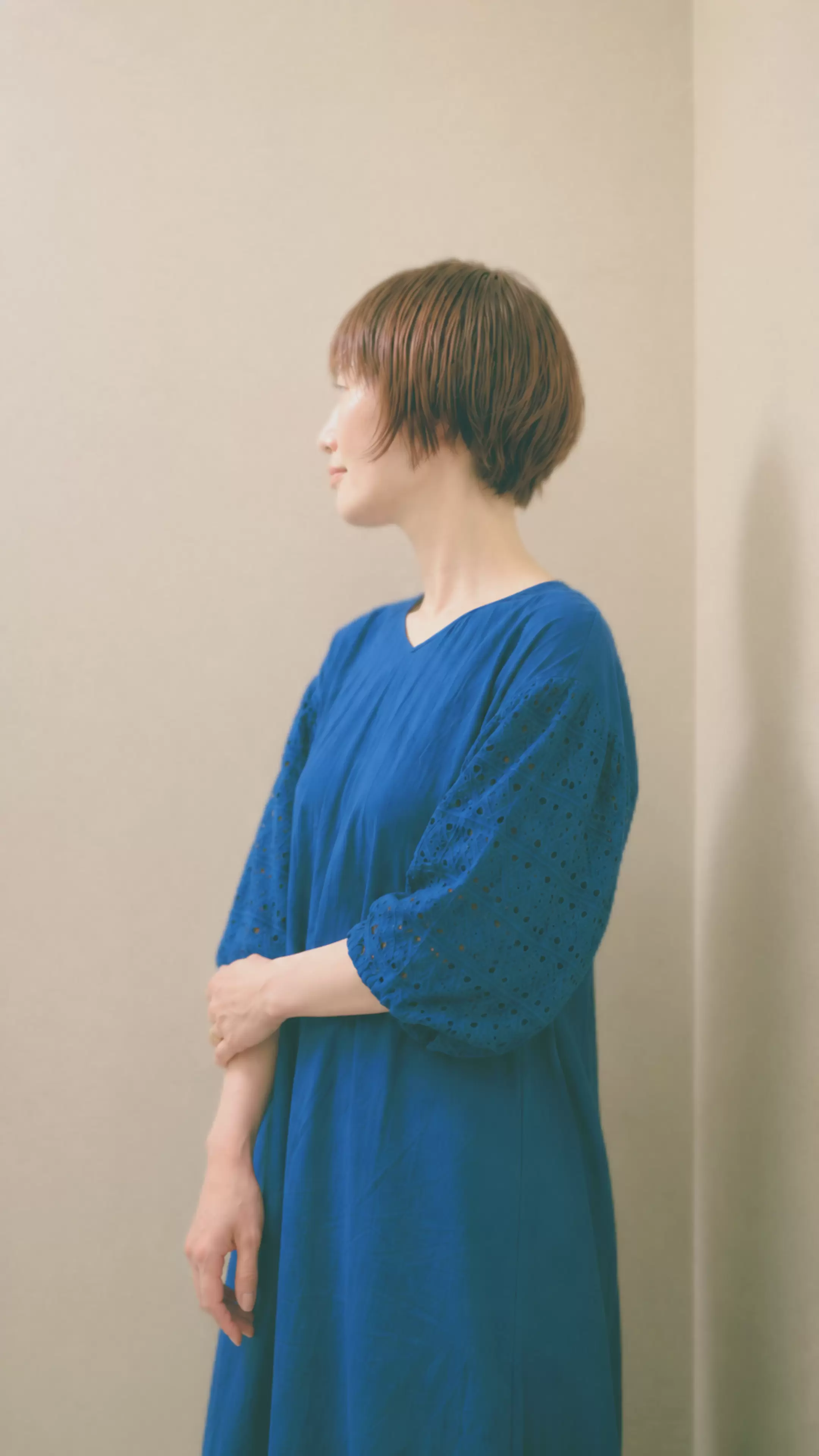 自然なブラウンのショートヘアと鮮やかなブルーの服を組み合わせたスタイル